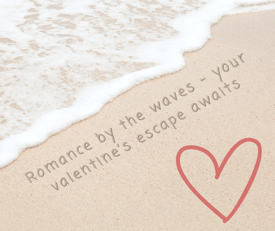 Waves gently wash over sandy beach with text, Romance by the waves - your valentine’s escape awaits, and a simple red heart drawn on the sand.